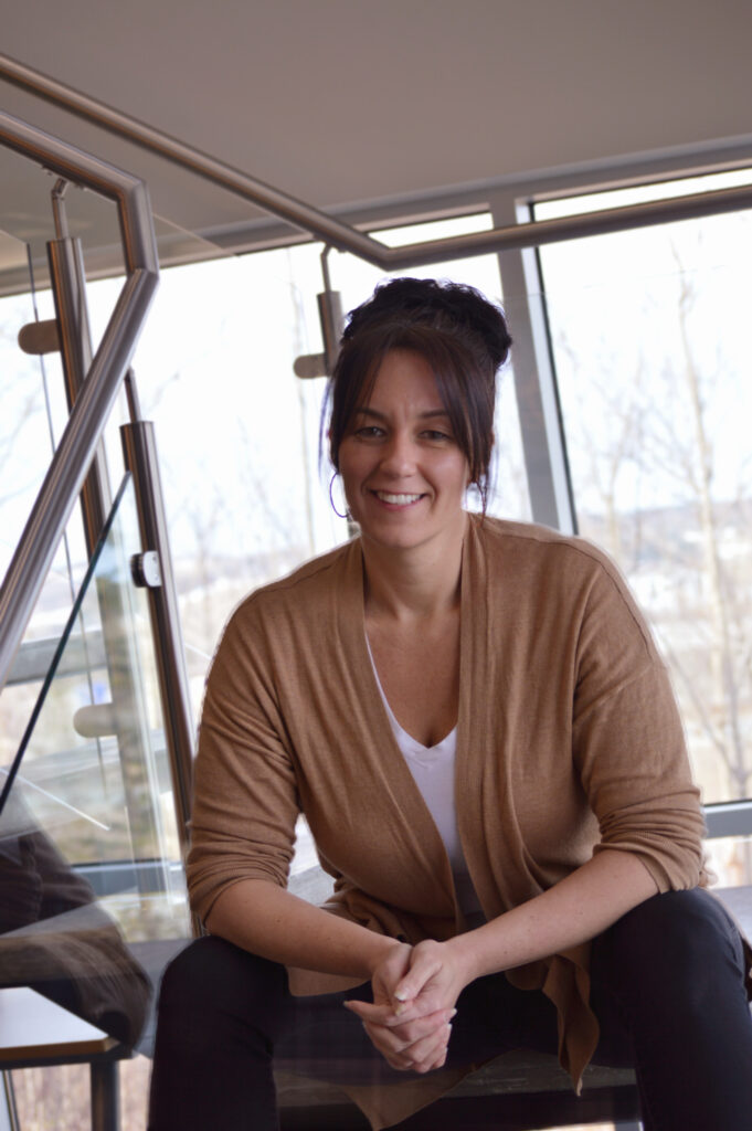 Femme assise souriante à l'intérieur.